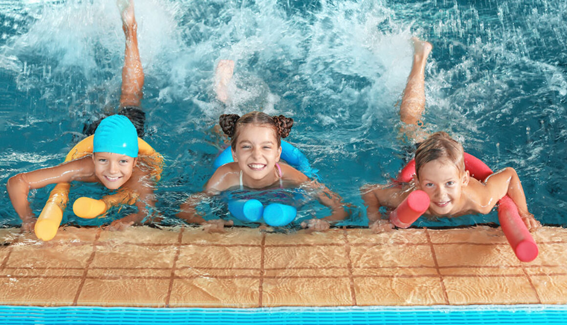 Little kids with swimming noodles in indoor pool